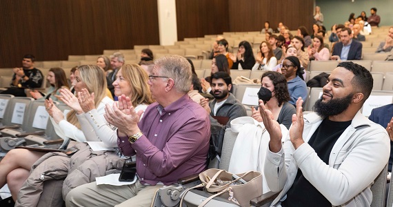 Audience members clap for awardees in auditorium space in Nesbitt Hall